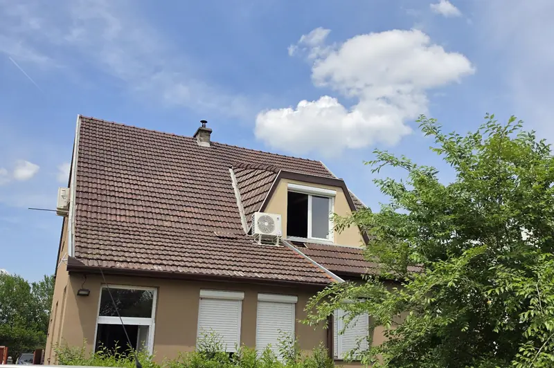 Családi ház, a tetőtéri ablak mellett a tetőn klíma kültéri egysége
